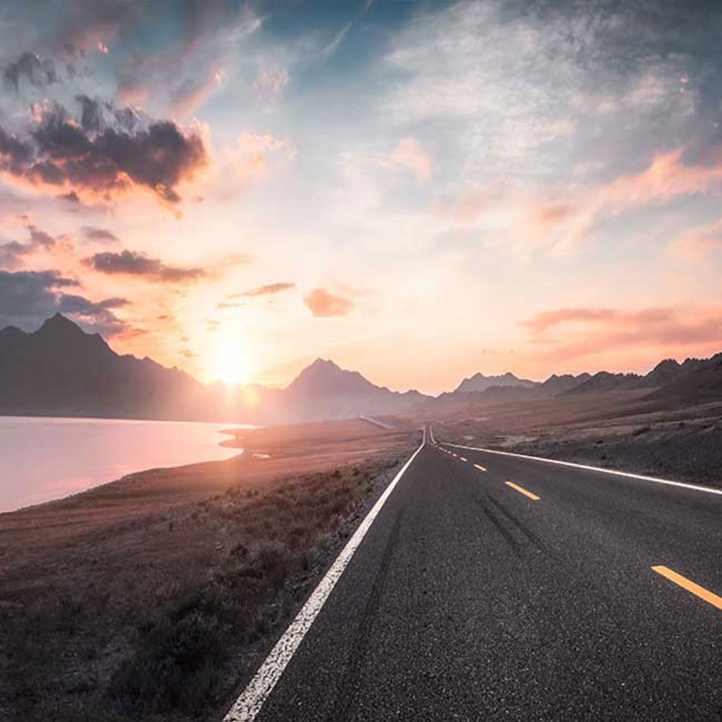 roadway leading towards the mountains with clouds above, Public Cloud | DXC Technology